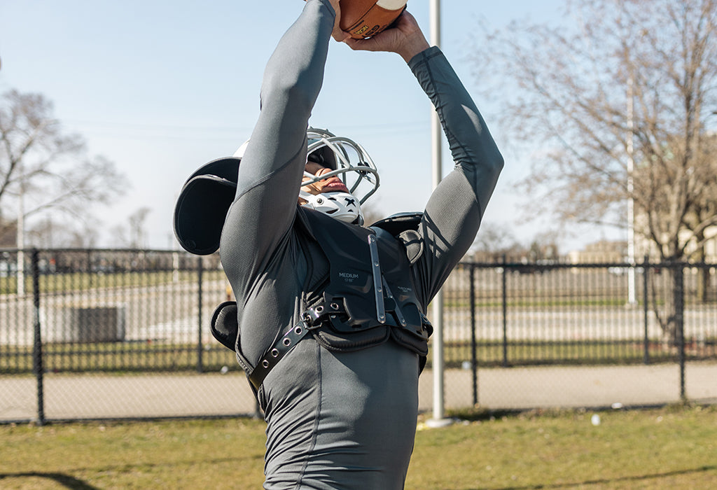 A football player catching a football wearing Xenith Velocity Pro Light shoulder pads.