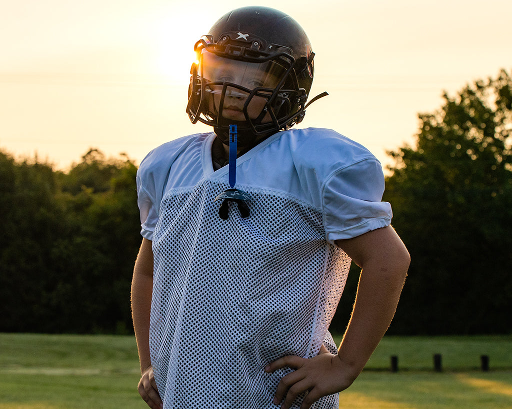 A youth football player standing, looking at the camera with his hands on his hips.