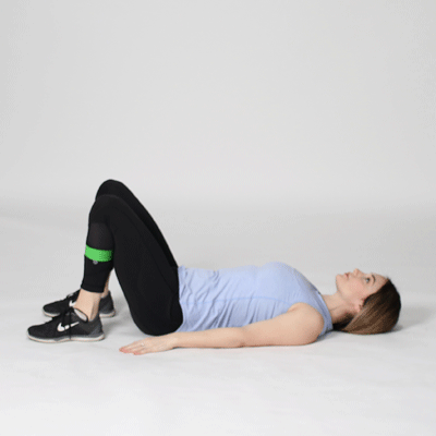 A woman doing banded glute bridge abduction exercise