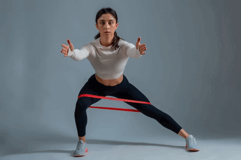 A woman doing lateral lunges with resistance bands