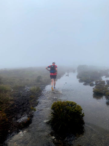 trail runner runs the overland track covered in water