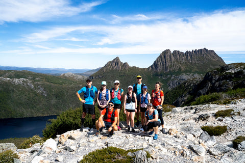 A group of very happy looking trail runners pose smiling at the camera in front of cradle mountain