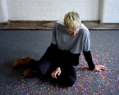 Hanny Allston sits on the floor, surrounded by brightly coloured confetti