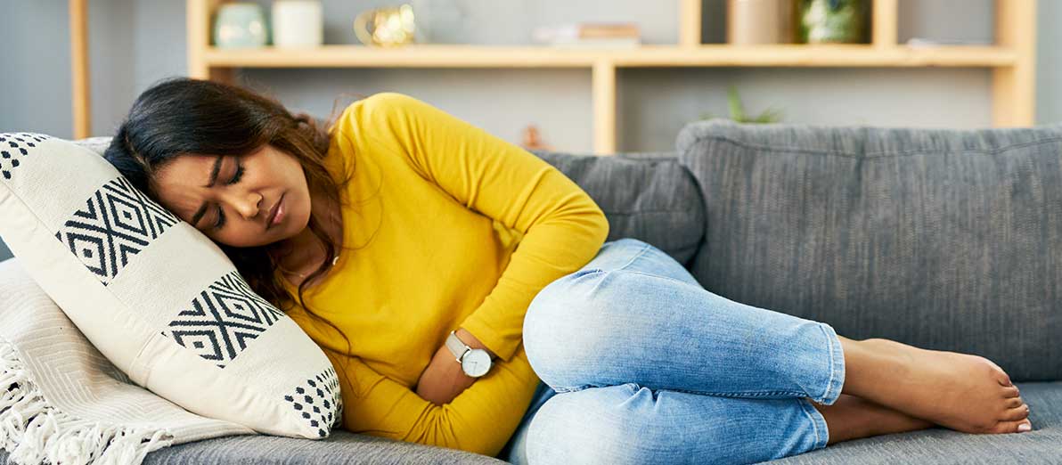 Woman lying on a couch holding her bloated tummy