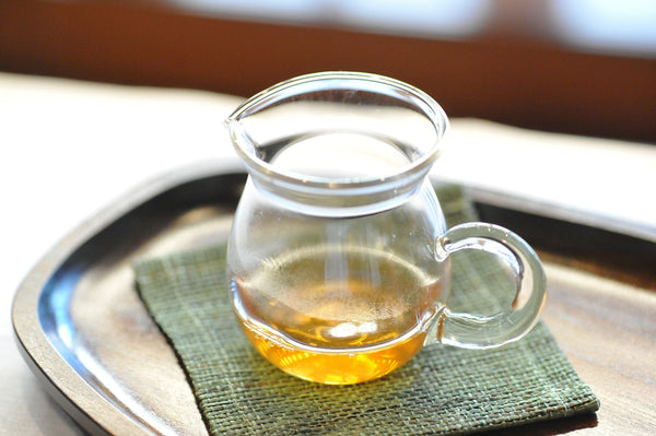 Liquid White tea in transparent mug on wooden tray