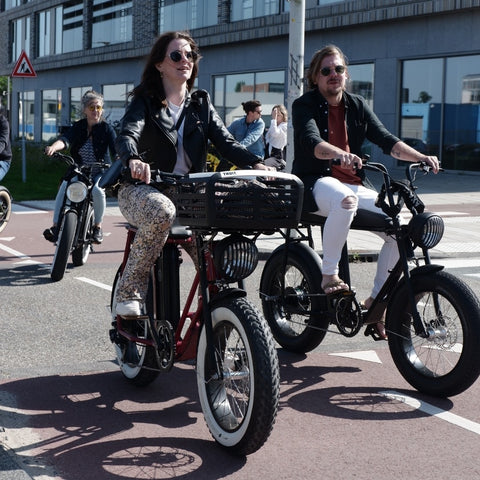 Couple in Amsterdam riding fat tire moped-style electric fat bikes uni mk urban drivestyle