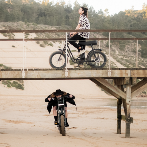 two riders having fun in two 50 Rebels ebikes near some dunes on the beach