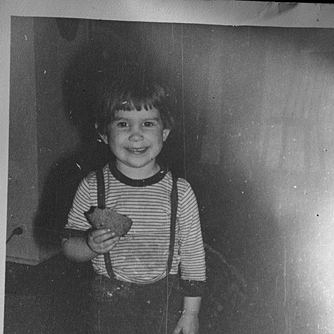 Lex as a small child with a wide grin, holding a very large cookie