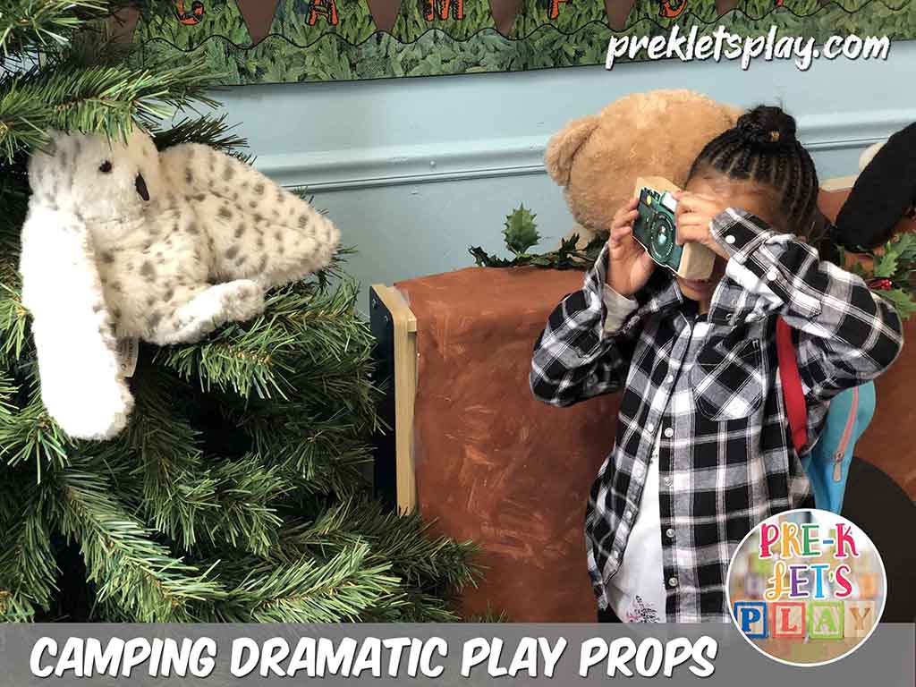 Girl Student that loves to play and learn with pretend play props in the camping dramatic play center. A classroom favorite is to turn a block into a pretend camera and take pictures of stuffed woodland animals, Download this Prek Let’s Play resource and get more great prop ideas like this for imaginative preschool play.