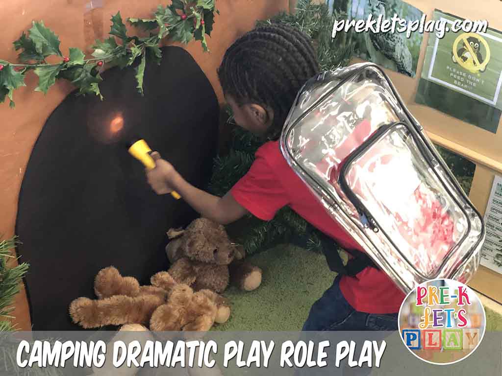 Kids love to role play in this dramatic play camping theme. This student using a flashlight and pretending to go hiking into a pretend play bear cave.