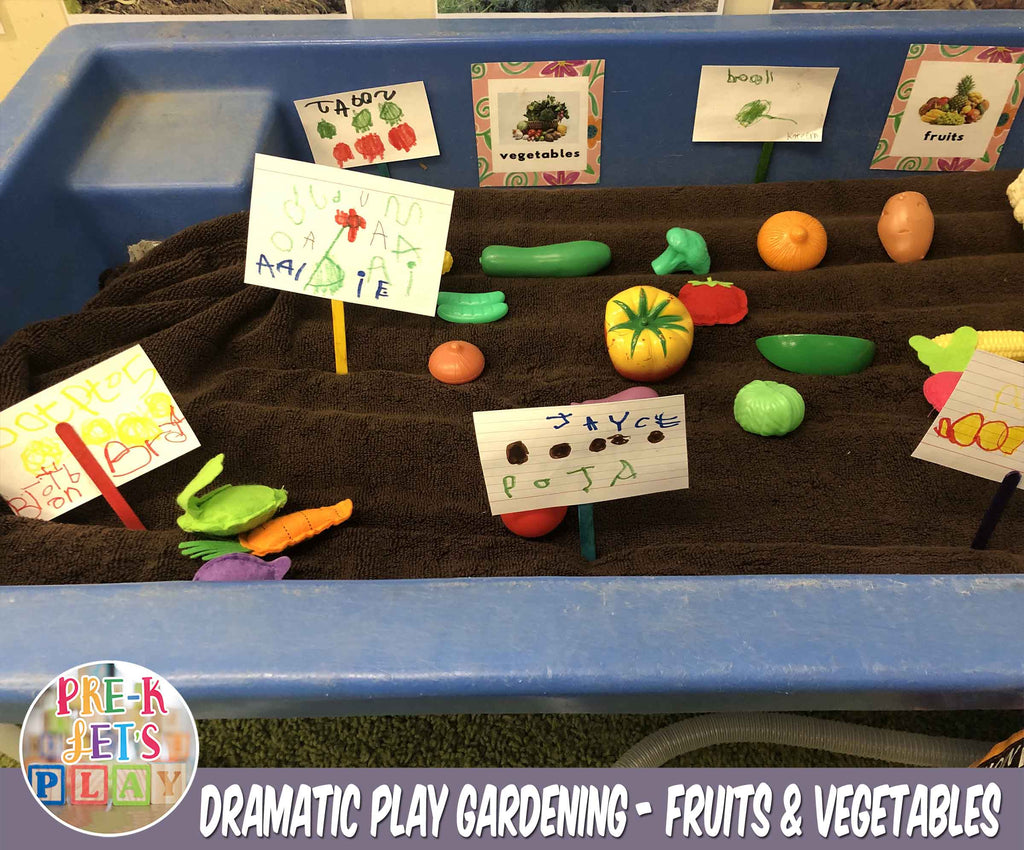 Plastic toy fruits and vegetables are placed inside a large sandbox to make it look like a pretend play gardening bed. These toy props were paired with hand drawn signs made by our preschoolers.