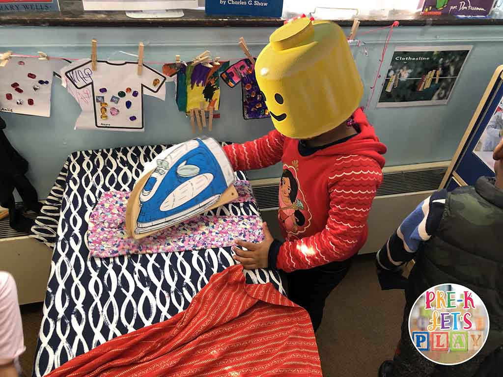 A student ironing clothes for pretend play in laundromat dramatic play area.
