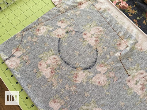 Floral fabric on a light green cutting mat. Fabric is marked as described in paragraph.