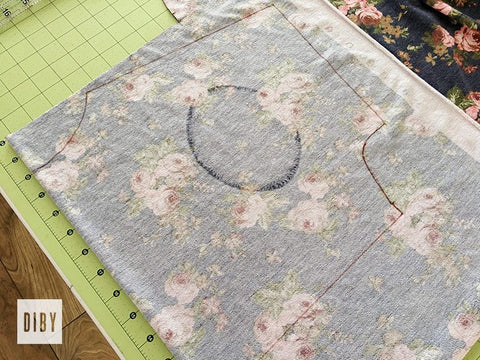 Wrong side of dark blue floral fabric with cutting markings on a green cutting mat.