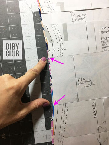 Photo of the pattern piece sitting on top of the swim fabric. Arrows are point to the two locations to be marked on the fabric.