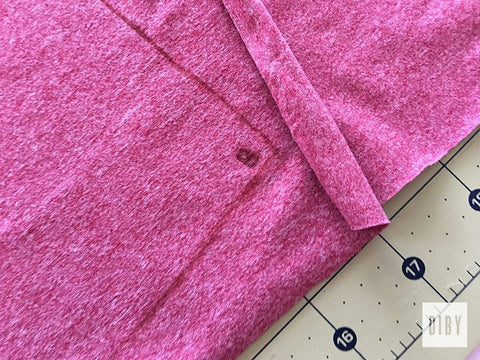 Wrong side of pink knit marked with "B" on a green cutting mat.