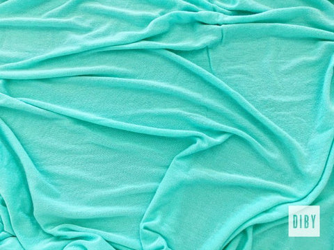 A piece of blue green rayon spandex fabric.