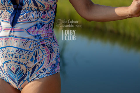 Picture of a woman in the swimsuit standing next to a lake. 