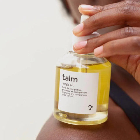 Woman holding Talm's nourishing body and face care oil on her shoulder to nourish and prevent stretch marks