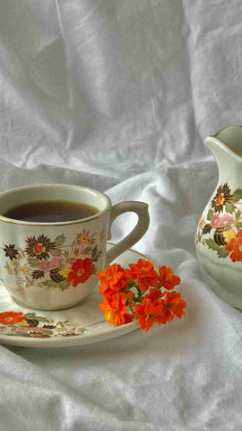 Infusion de plantes et de fleurs servi dans une tasse en porcelaine dans un lit blanc pour calme les syndromes prémenstruels