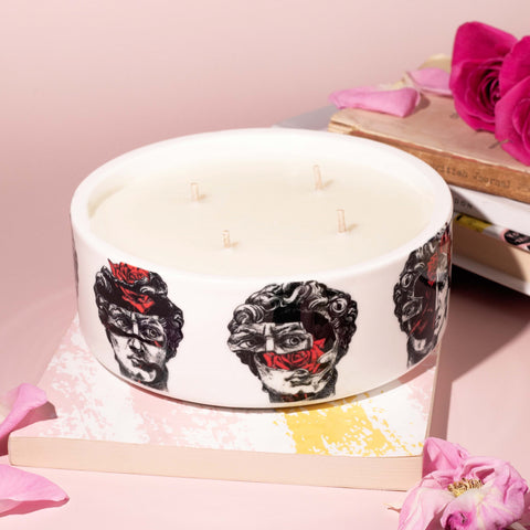 A big four wick scented candle in designed ceramic vessel featuring sketch-like david portrait with roses coming from his face.