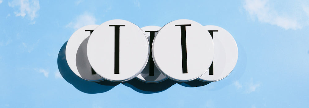 tuttofare tallow balm in a stack of five jars set against a blue sky background with clouds