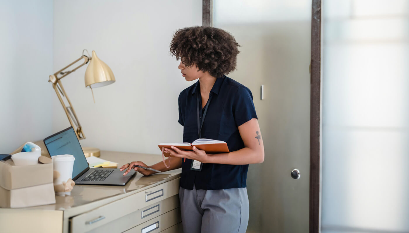 woman taking a standing break at a file cabinet turned standing workspace