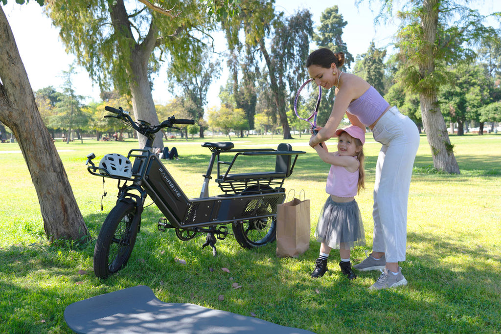 woman and child playing tennis with a cargo ebike on the grass
