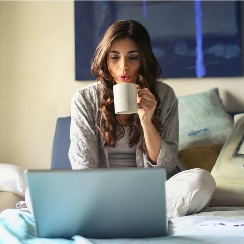 woman working on her laptop from bed