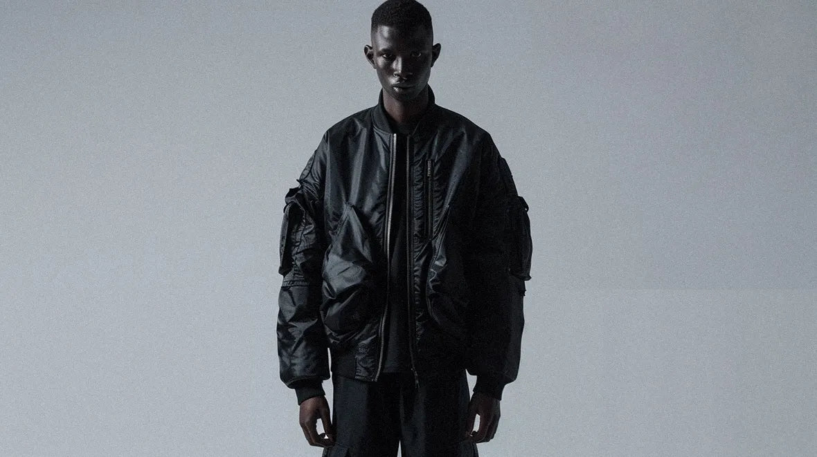 A minimalist style is captured with a person in a black bomber jacket against a neutral backdrop.