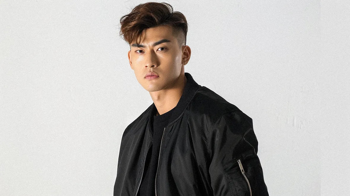 The young individual wears a black techwear bomber jacket, presenting a moody expression.