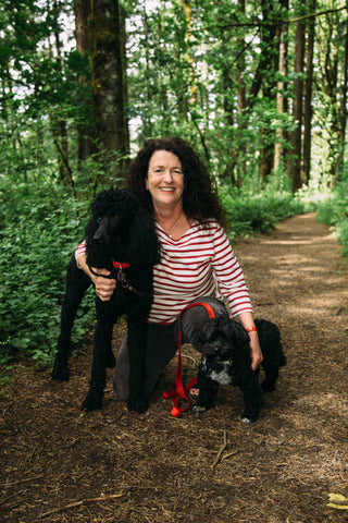 Founder Kate McCarron kneeling with her two dogs on a hike