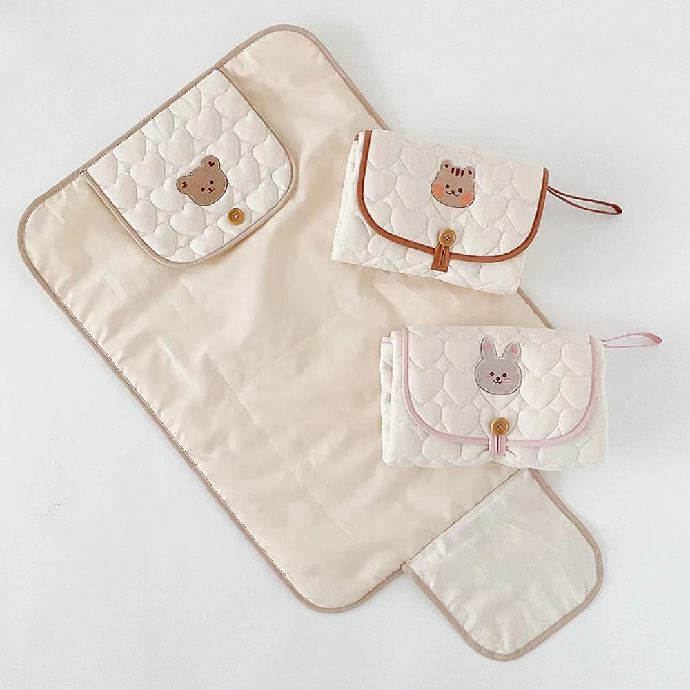 A foldable portable diaper changing pad with a cute animal pattern.