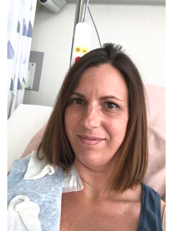 Diane liegt auf Krankenhausbett nach Brust-OP, Kühlakkus auf operierter Brustseite