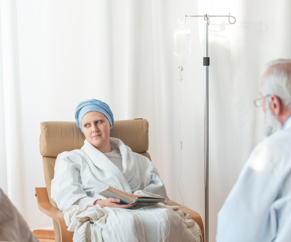 Frau sitzt mit Buch auf Stuhl während Chemotherapie