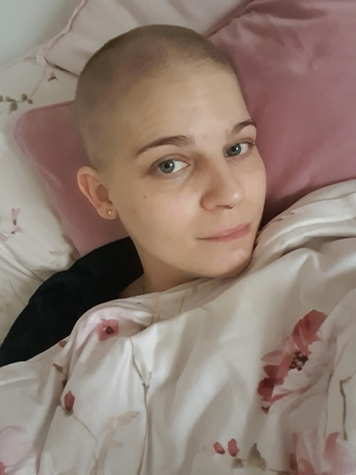 Carina liegt im Bett, trauriger Blick in die Kamera