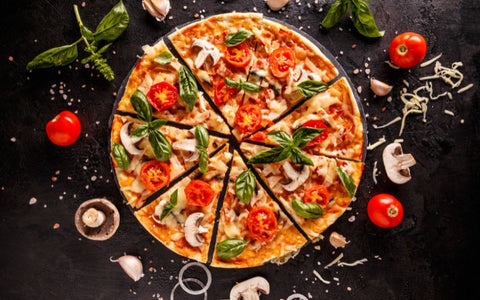 A pizza with tomatoes and mushrooms on a black background.