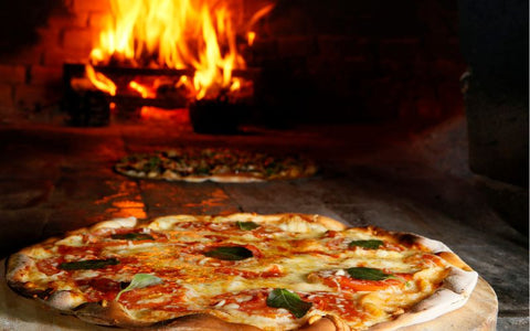 A pizza is sitting on a wooden board in front of a fireplace.