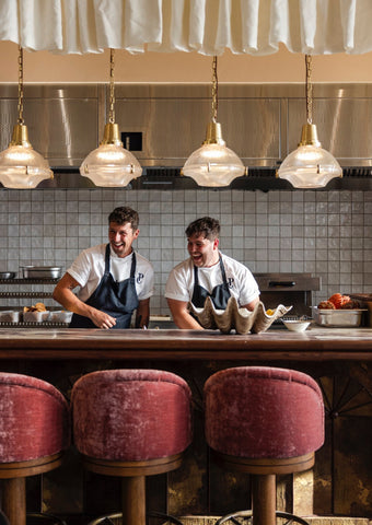 4 dome pendant lights illuminating an open kitchen with 2 chefs demonstrating their cooking skills