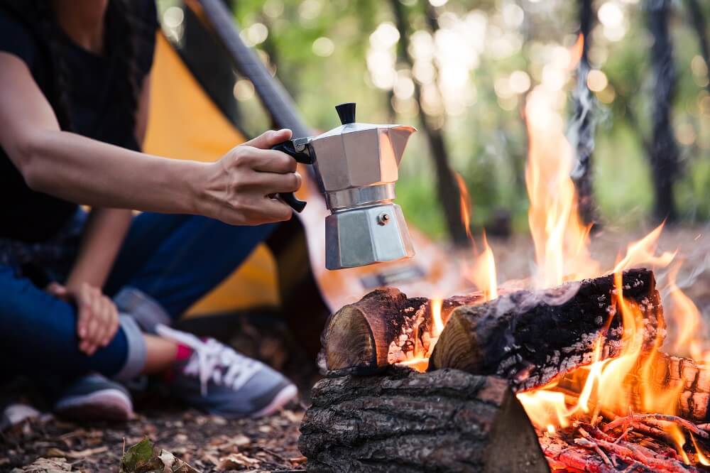 A couple making good coffee using percolator on campfire