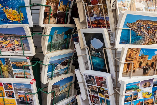 Assortment of colorful postcards in a rack, offering a glimpse into traditional travel keepsakes for a nostalgic travel memorabilia article.