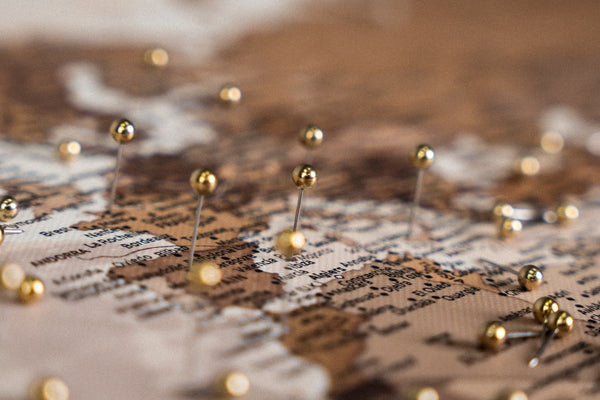 Close-up of a world map with golden pins marking traveled destinations, perfect for a travel tracking.