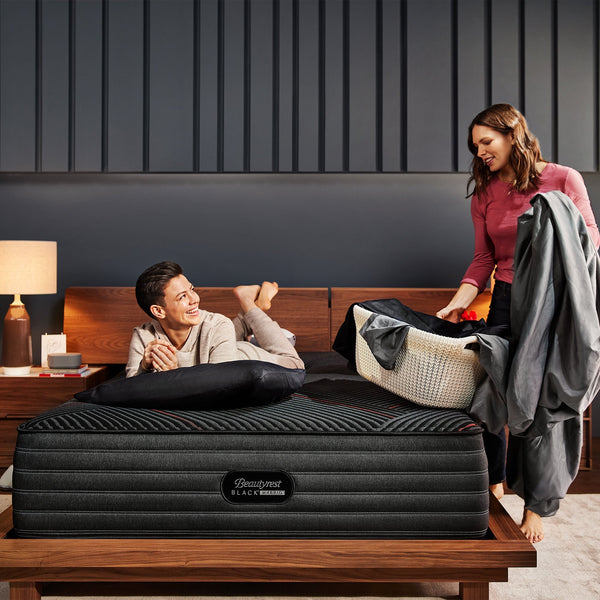 Couple Relaxing On A Beautyrest Black Hybrid C-Class Medium Mattress On Bed Frame In Bedroom