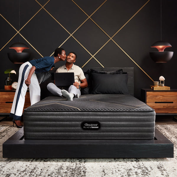 Woman Kissing Man On The Cheek While Relaxing On A Beautyrest Black Hybrid K-Class Firm Mattress