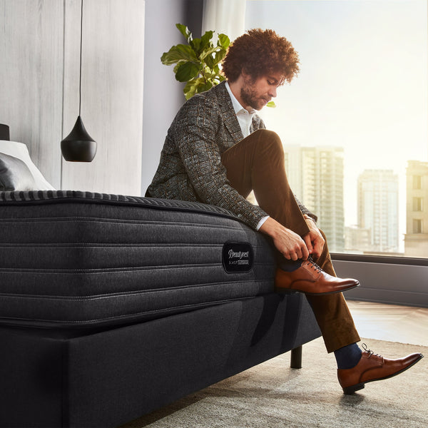 Man Tying Shoe While Sitting On The Edge Of A Beautyrest Black Hybrid L-Class Medium Mattress