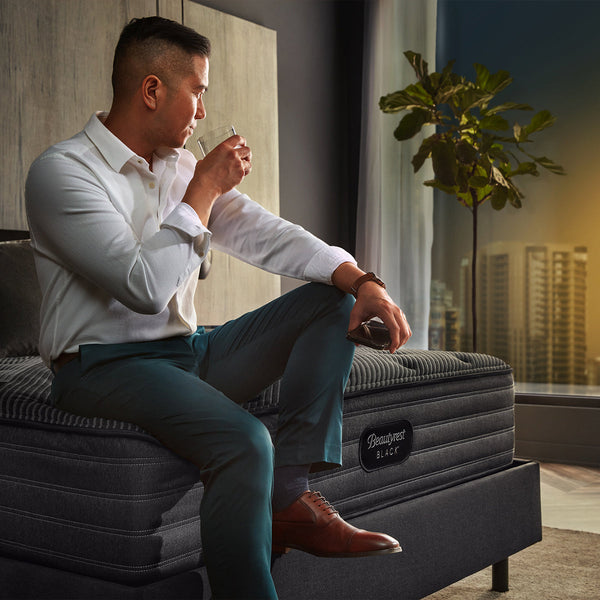 Man Enjoying a Drink While Sitting On A Beautyrest Black L-Class Medium Mattress