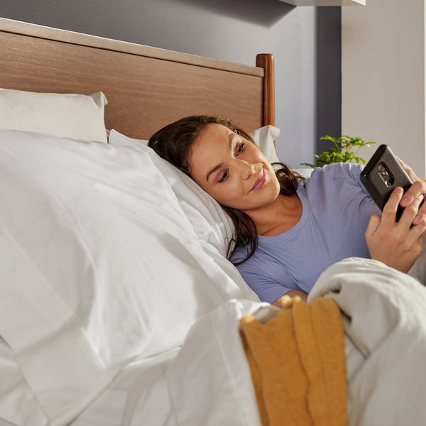 Woman Relaxing In Bed On A Sealy Ease 4.0 Adjustable Base