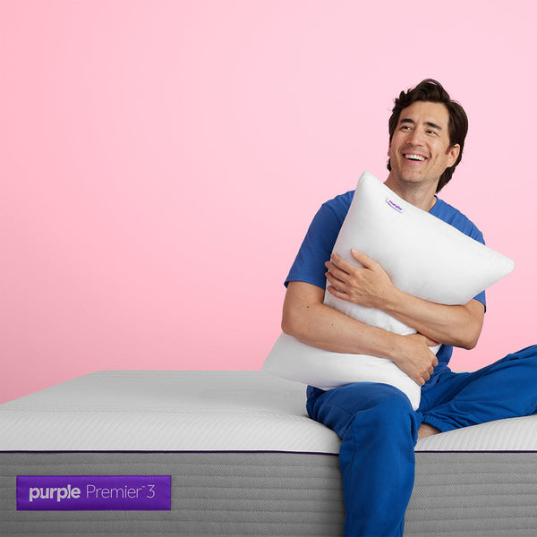 Man Holding Pillow Sitting On The Purple Hybrid Premier 3 Mattress