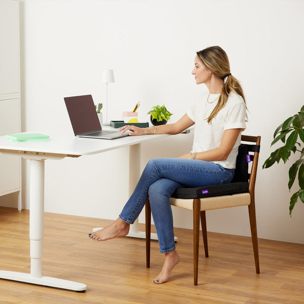 Woman Sitting On A Purple Double Seat Cushion Placed On A Chair While Working At Her Desk