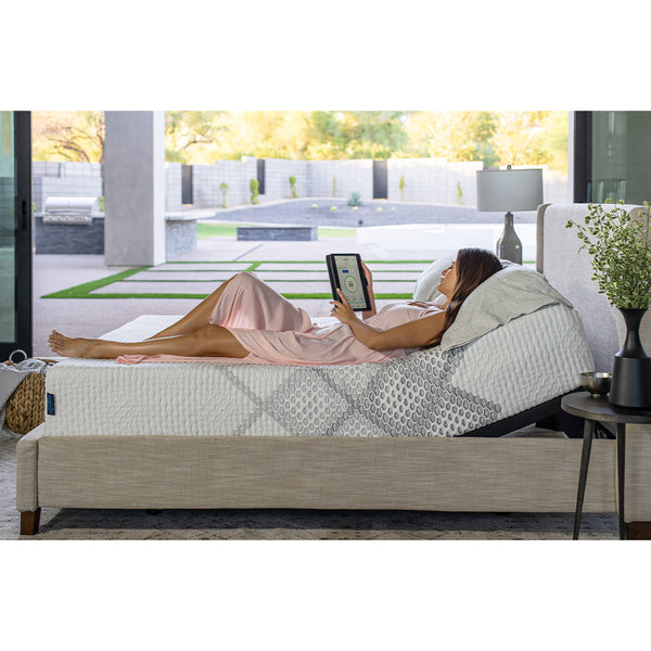 Woman using a smart device to adjust the settings on a SmartLife Lily Medium Mattress on an adjustable base